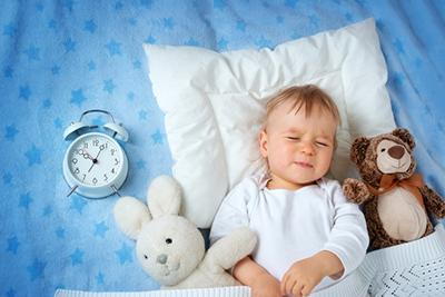 Toddler-sleeps-with-stuffed-toys-and-alarm-clock