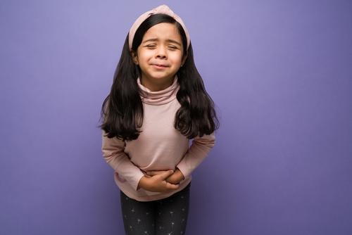 Child experiencing stomach ache on a violet background