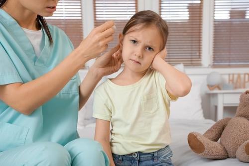 Pediatrician treating a child with an ear infection by examining the ear and providing care to support recovery and improve ear health.