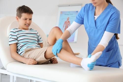 Pediatrician examining a child with leg pain during a clinical evaluation.
